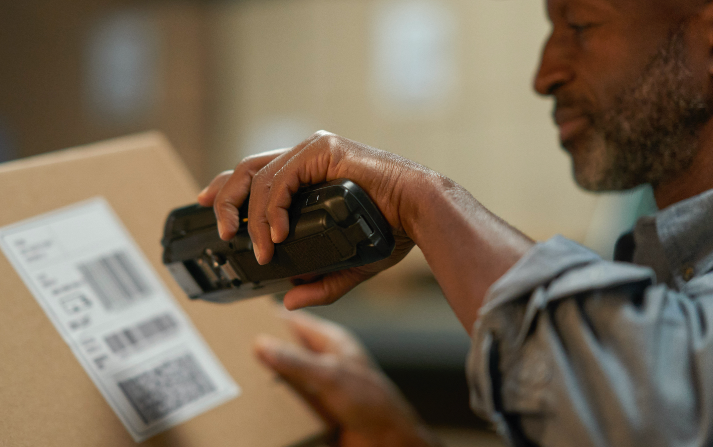 Man with barcode scanner scanning a label posted on a brown box.