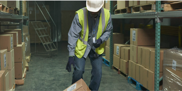 A man carrying a box in a warehouse.