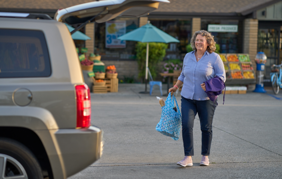 A woman carrying groceries to her car.